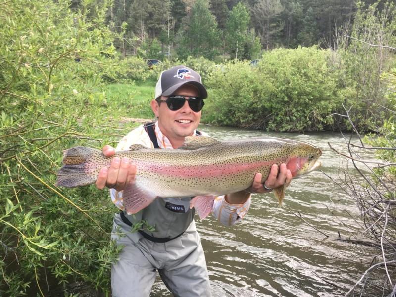 A man proudly displaying the huge trout he just caught