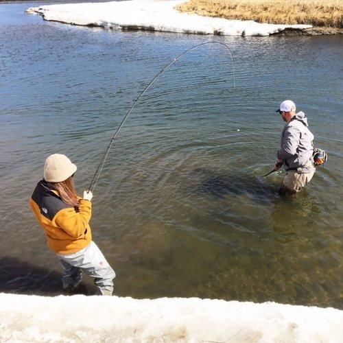 Two anglers wading in the river, casting their lines