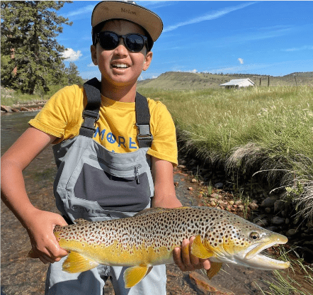 Young fisherman holding a large brown trout